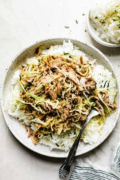 a white plate topped with shredded cabbage next to a bowl of rice and a spoon