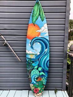 a surfboard is sitting on the side of a building with an ocean scene painted on it