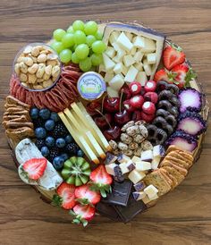 an assortment of cheeses, crackers, and fruit arranged in a circular basket