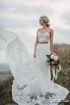 a woman in a white wedding dress standing on top of a hill