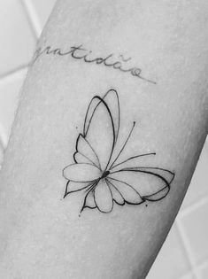 a black and white photo of a butterfly tattoo on the left inner arm, with words written in cursive writing