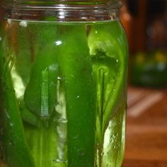 a jar filled with pickles sitting on top of a wooden table