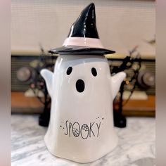 a ceramic teapot with a black and white witches hat on it's head