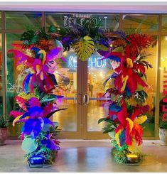 an entrance to a store decorated with fake flowers and leaves in front of the door