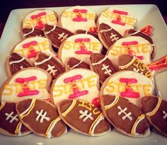 decorated cookies are arranged in the shape of footballs on a white platter with orange and pink icing