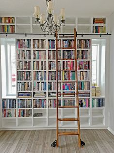 a ladder is in front of a bookcase full of books and lights on the wall