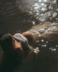 a woman is floating in the water with her head on her back and eyes closed