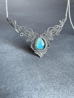 a silver necklace with a blue stone in the center