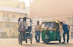 three men are standing next to a green and yellow rickshaw