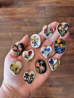 a person's hand holding several different types of flowers and hearts shaped buttons on them