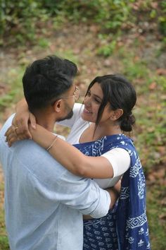 a man and woman embracing each other in the woods