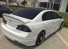 a white car parked in front of a building with solar panels on it's roof