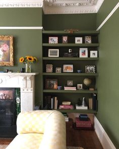 a living room filled with furniture and a fire place next to a wall mounted book shelf