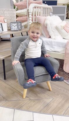 a little boy sitting on top of a gray chair