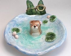 a ceramic animal in a bowl with lily pads and water lilies on the bottom