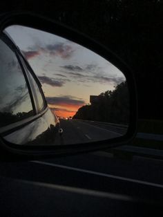 the sun is setting in the side mirror of a car