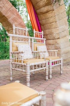 two white chairs sitting next to each other on top of a brick floor