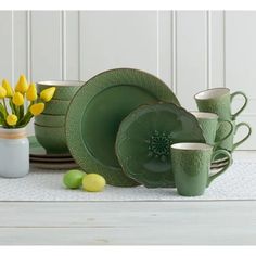 a table topped with green plates and cups