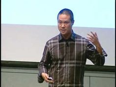 a man standing in front of a projector screen giving a presentation on his cell phone