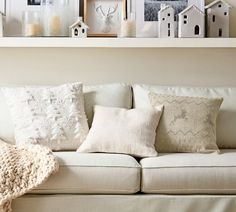 a white couch with pillows and pictures on the shelf above it in a living room