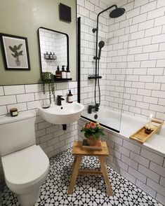 a white toilet sitting next to a bath tub in a bathroom with black and white tiles