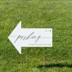 a white sign that says parking on it in the middle of green grass with an arrow pointing to the right