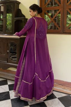 Purple anarkali with full sleeves, metallic lace work details, Mughal inspired paisley pattern, tonal thread chain stitch, sequin and bead embroidery. Paired with flared sharara with inserted zari godet multi panels and inner blouse.
Components: 3
Pattern: Embroidered and Embellished
Type Of Work: Thread Chain Stitch, Sequin and Bead Work
Neckline: V Neck
Sleeve Type: Anarkali: Full Sleeves, Blouse: Sleeveless
Fabric: Chanderi Silk, Zari, Lining: Cotton Silk
Color: Purple
Other Details: 
Side hi Purple Chanderi Anarkali Set For Wedding, Anarkali Style Long Sharara With Dabka, Anarkali Long Sharara With Dabka, Designer Purple Churidar With Cutdana Detail, Transitional Purple Anarkali Set For Designer Wear, Long Designer Sharara For Navratri, Long Choli With Cutdana For Weddings, Long Lehenga With Dabka For Diwali, Purple Anarkali Set For Wedding And Eid