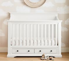 a white crib with two drawers and a mirror on the wall next to it