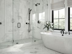 a white bathtub sitting next to a window in a bathroom