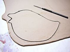 a piece of clay with a bird design on it and a pencil laying next to it