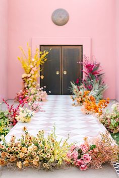 a room filled with lots of flowers and plants on top of a checkered floor