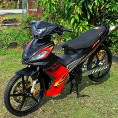 a red and black motorcycle parked in the grass