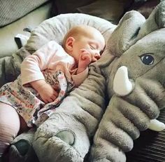 a baby laying on top of an elephant stuffed animal