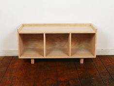 a wooden shelf sitting on top of a hard wood floor next to a white wall