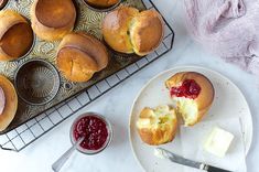 muffins with butter and jam are on a plate next to a cooling rack