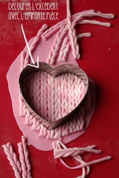 a heart shaped object sitting on top of a table next to knitting needles and yarn