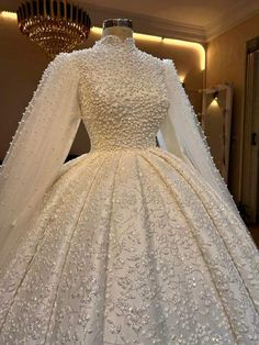 a white wedding dress with long sleeves and beading on the skirt is displayed in front of