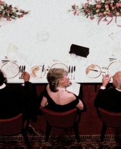 three people sitting at a table with plates and utensils in front of them