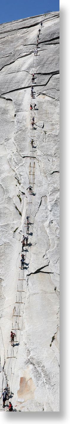 a group of people climbing up the side of a snow covered mountain with skis on it