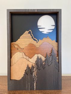 a wooden frame with mountains and trees on it