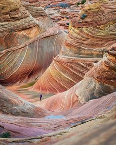 a person standing in the middle of a canyon filled with red and white rocks,