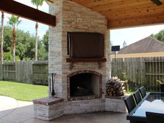 an outdoor fireplace in the middle of a patio with a table and chairs around it