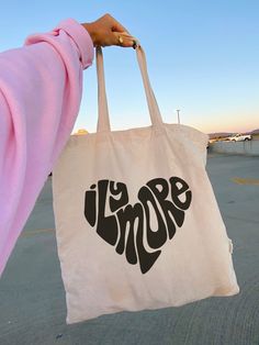 Show your love with this totally cute ILY MORE HEART TOTE! This trendy tote is made of 100% cotton and has a 6oz weight that’s perfect for carrying your everyday necessities. Plus, with its fun design, it’ll fill your heart (and your bag) with love! size: 22" handles 14 1/2" W x 15 1/2" H Tote Bag Diy Pattern, Bag Design Ideas, Tote Bad, Diy Tote Bag Design, Bags Ideas, Best Tote Bags, Diy Bag Designs