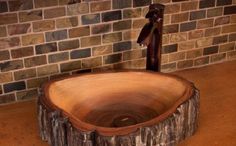 a wooden sink in front of a brick wall with a faucet on it