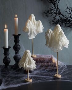 three candles and some fake ghost decorations on a table