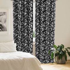 black and white curtains in a bedroom next to a window with an image on the wall