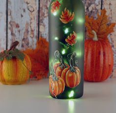 a lighted bottle with pumpkins and leaves on it