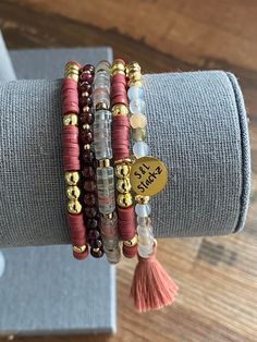 This 4mm maroon consists of 5 bracelets, perfect for everyday wear and every occasion.  *In this stack you will receive* * 2 Heishi bracelets with gold round beads and an S&L charm.   * White agate bead with 14k gold faceted, gold spacers and a dark pink tassel.  * Natural stone bead in clear and watermelon with gold spacers.  * Dark garnet bead with gold accent.   All S&L Stackz come in a muslin bag for easy storage and gifting! If you need a special gift for that someone, these stacks are perfect!  Bracelets are made with quality stretchy elastic material. Heishi bracelets have double elastic.  >> Try rolling one bracelet at a time << >>Do not over stretch<< > Please keep in mind, this stack is made to order. FINAL SALE > Color & size of beads may vary due to supply.  > Follow instructio Fall Heishi Bead Bracelets, Maroon Clay Bead Bracelet, Red Adjustable Heishi Beads Stretch Bracelet, Pink Heishi Beads Stretch Bracelet Stackable, Red Stackable Bracelet, Hand-strung Heishi Beads Stretch Bracelet, Gold Stretch Bracelet With Hand-strung Heishi Beads, Autumn Bracelet, Bracelet Diy