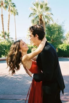 a man in a tuxedo and woman in a red dress are smiling at each other