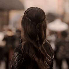 the back of a woman's head with braids in her hair walking down a street